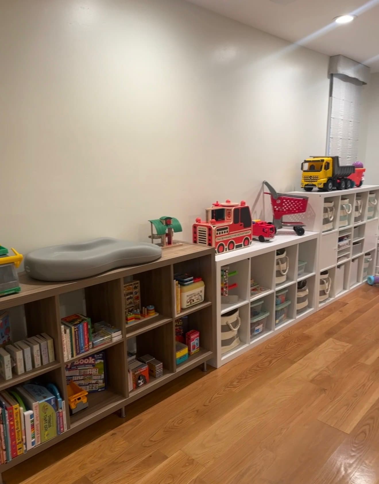 After: toys and books arranged in low shelves with fabric baskets and a clear floor